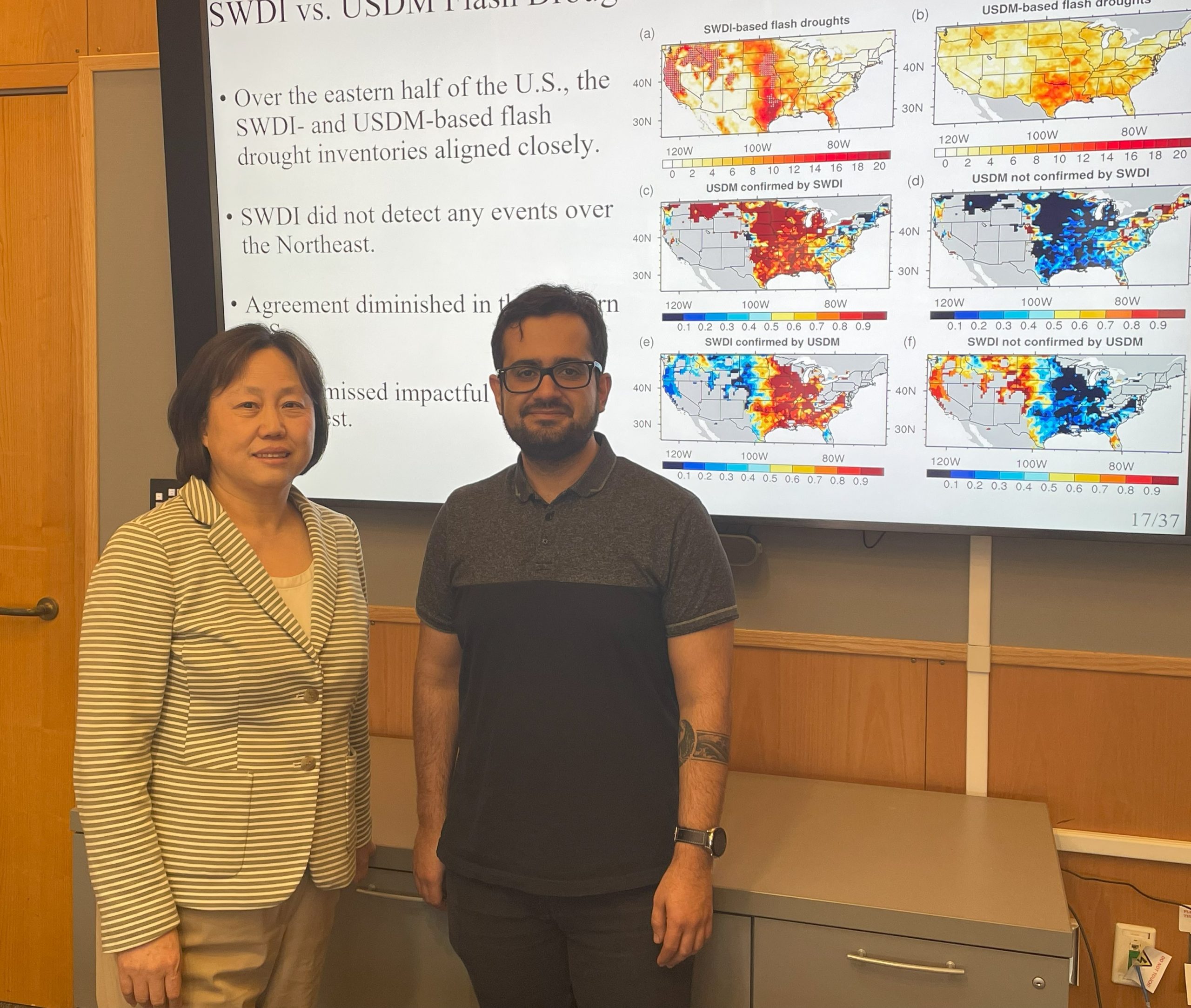 Koushan and Guiling standing next to a poster